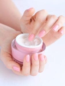 Woman with pink nails holding jar of cream